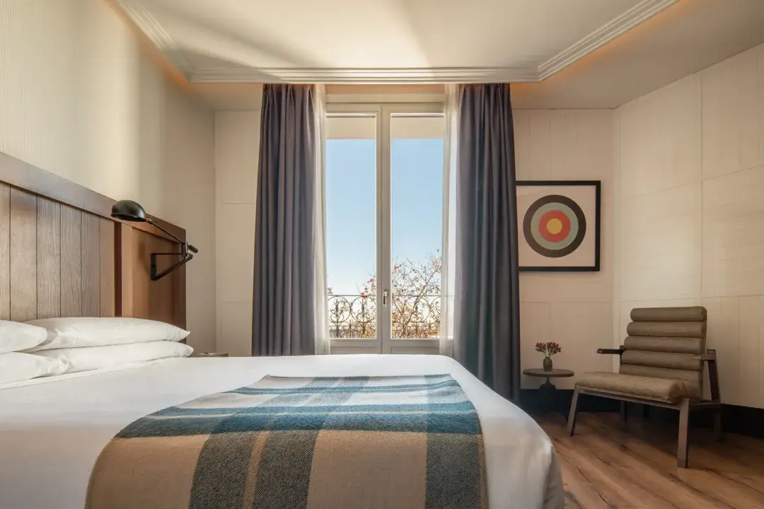 A guest room at Only YOU Hotel Atocha with a wooden headboard and a balcony window