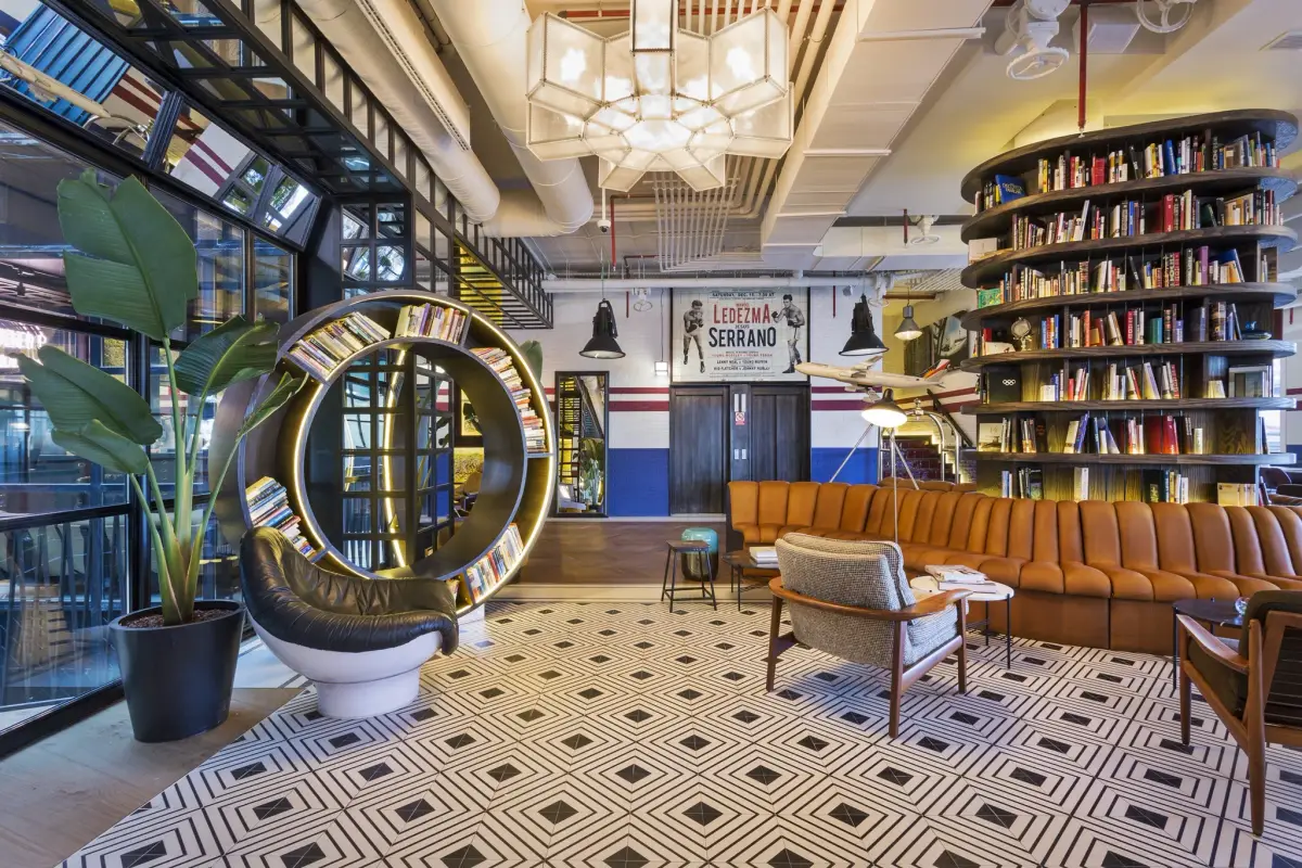 The lobby at Only YOU Hotel Atocha with a library wall, a patterned floor and a long tan banquette