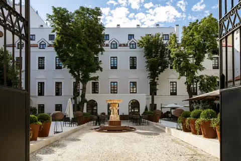 The courtyard garden at Gran Melia Palacio de los Duques with a stone fountain and the white palace behind