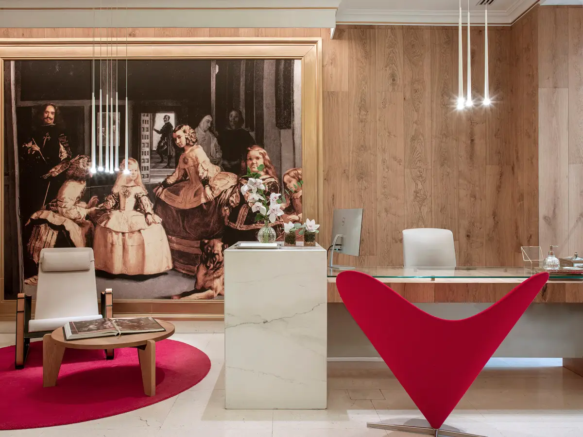The lobby at Gran Melia Palacio de los Duques with a large reproduction of Las Meninas behind the desk