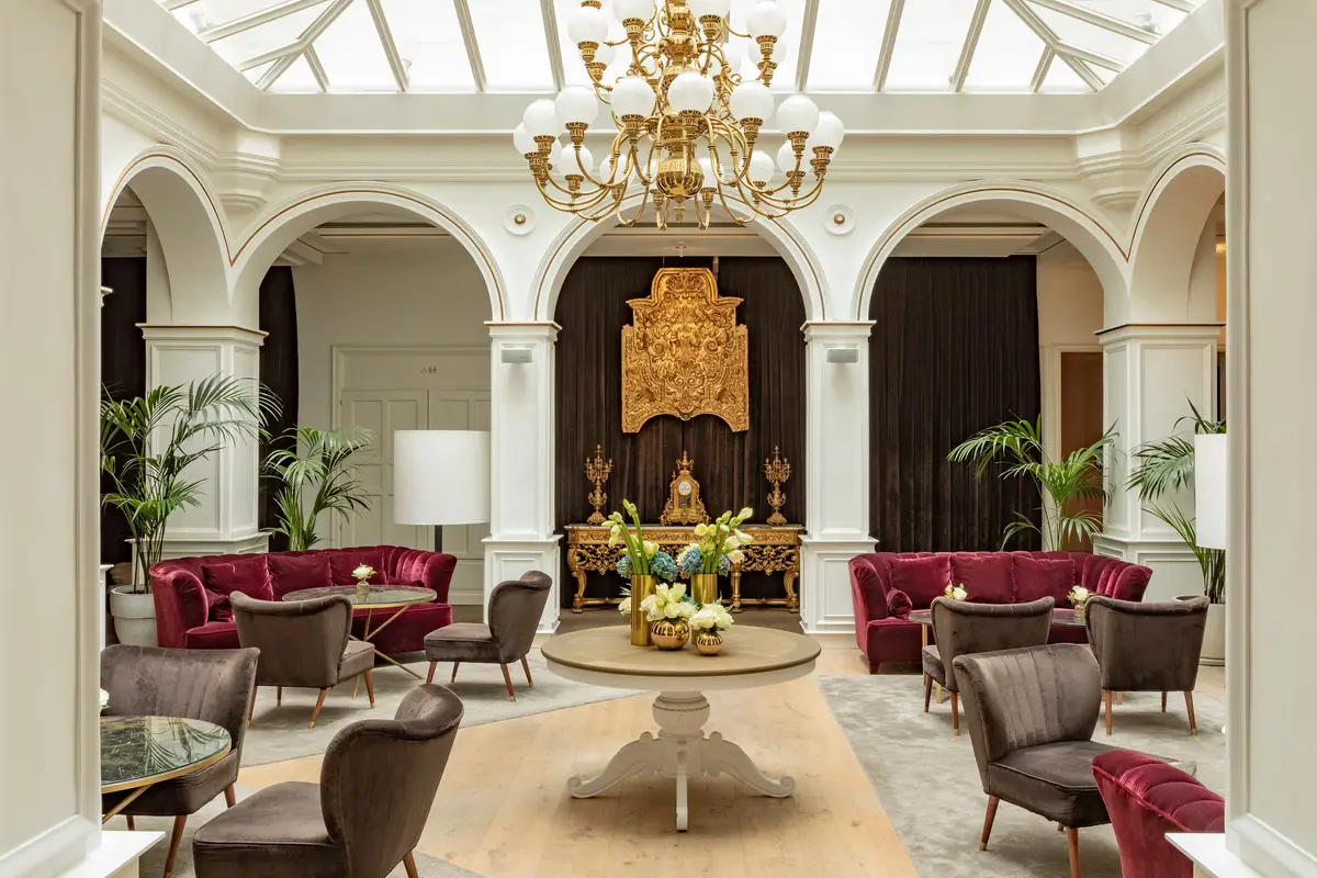 The glass roofed arcaded lounge at Gran Melia Palacio de los Duques with red velvet sofas