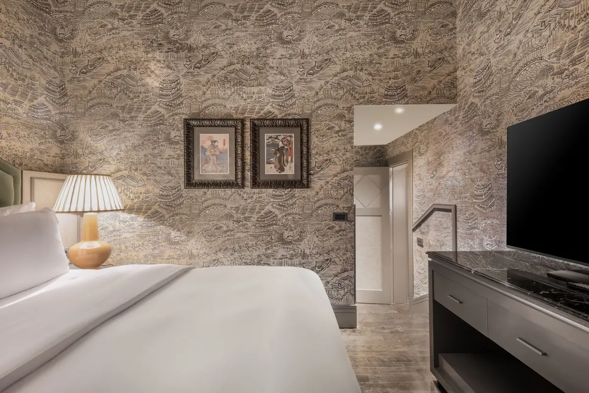 A guest room at Santo Mauro with a grey papered wall and a low upholstered bed