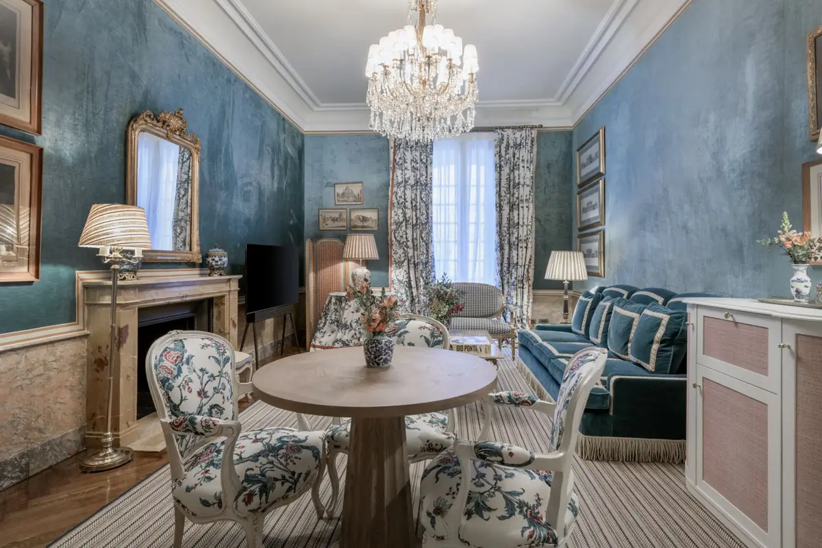 The blue salon of the Royal Suite at Santo Mauro with a chandelier and a marble fireplace