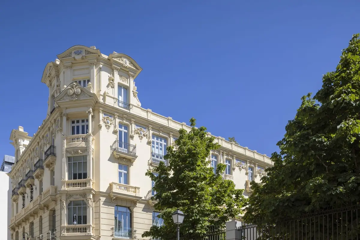 The stone facade of URSO Hotel and Spa above the trees on Calle Mejia Lequerica