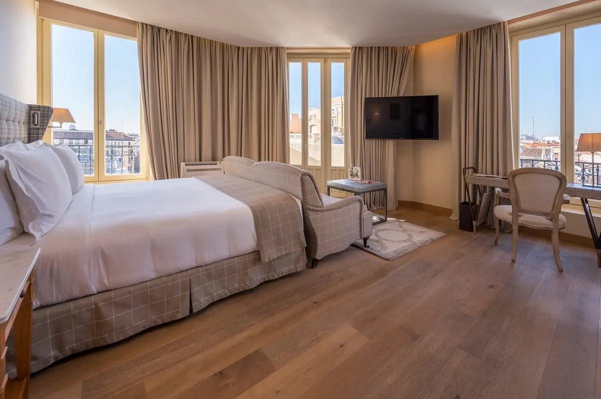 A bedroom at URSO Hotel and Spa with pale walls and tall windows over the street