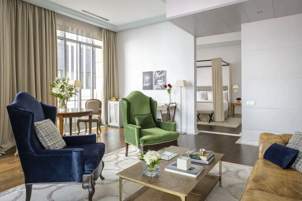 The sitting room of the URSO Suite with a blue and a green armchair and a low table
