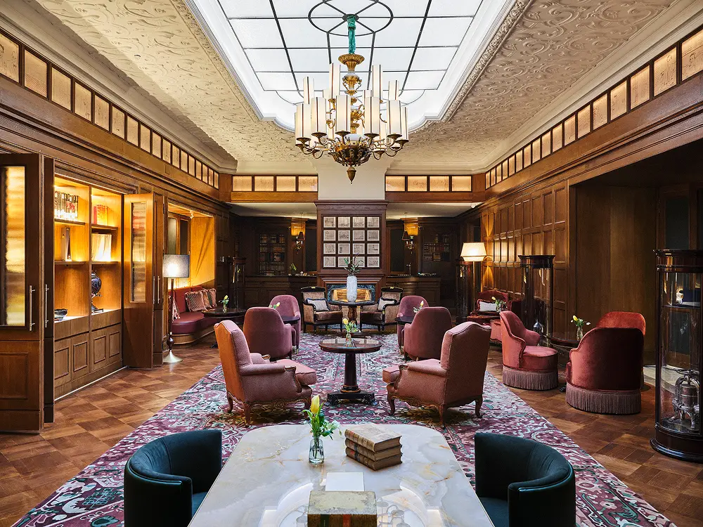The panelled bar at 27 Club in The Palace Madrid with a skylight and deep red armchairs