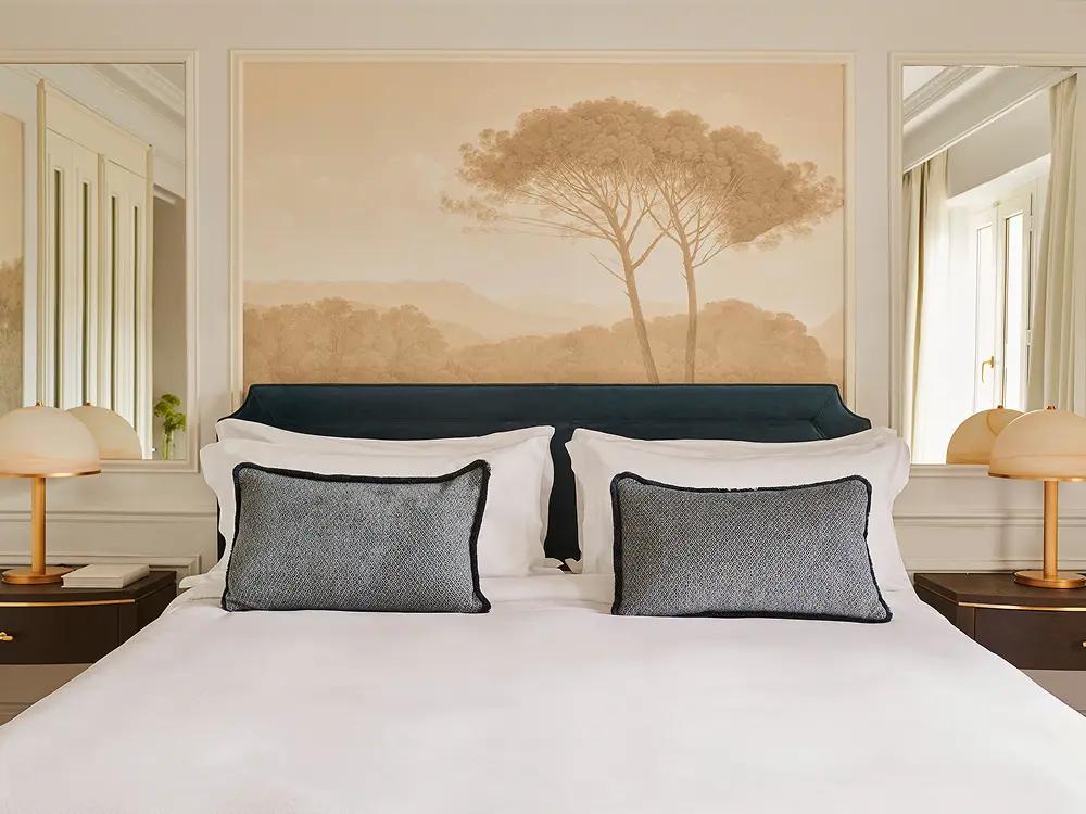 A guest room at The Palace Madrid with a hand painted tree mural above the bed