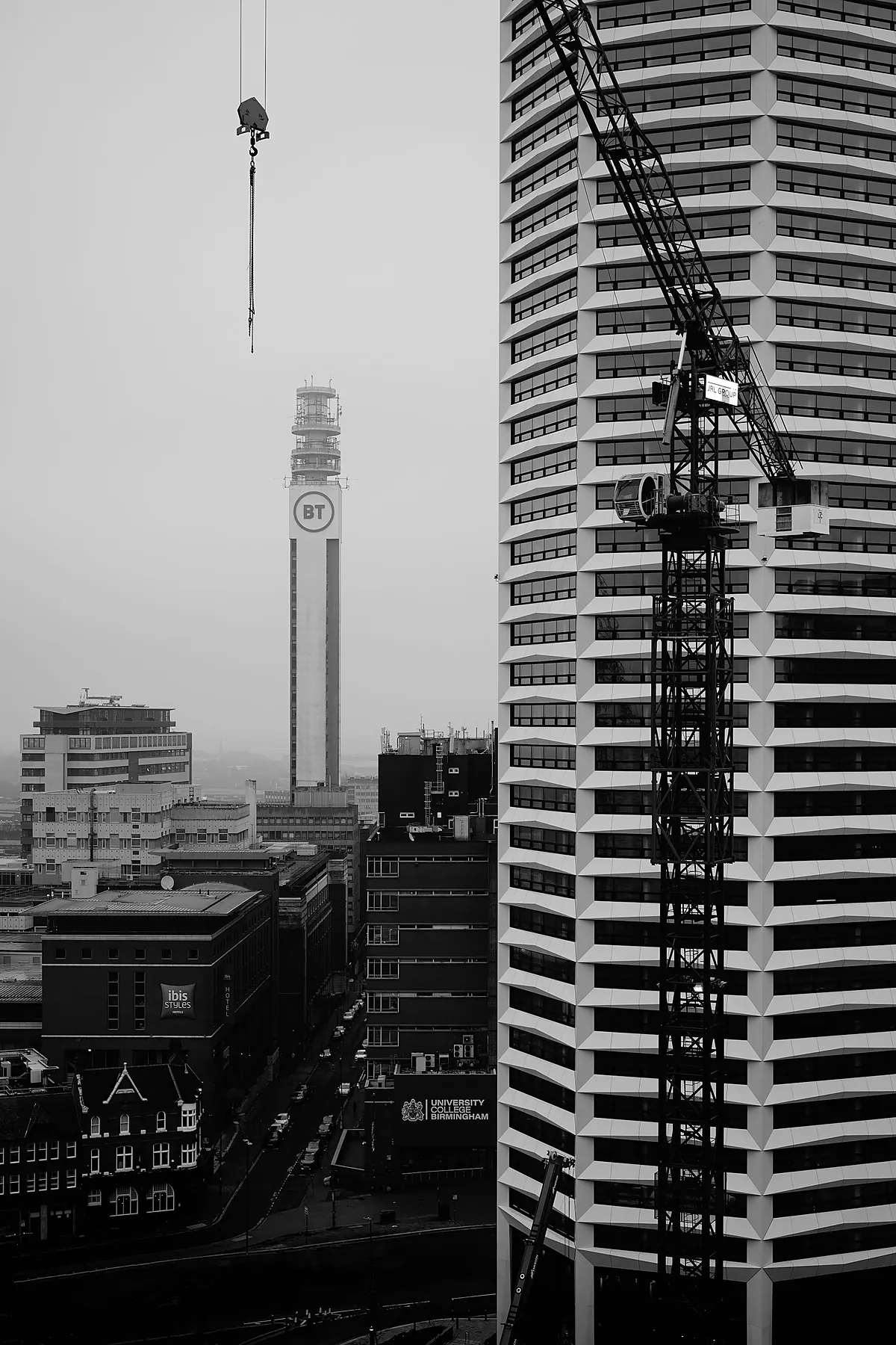 Unfinished towers behind a construction crane, shot in black and white