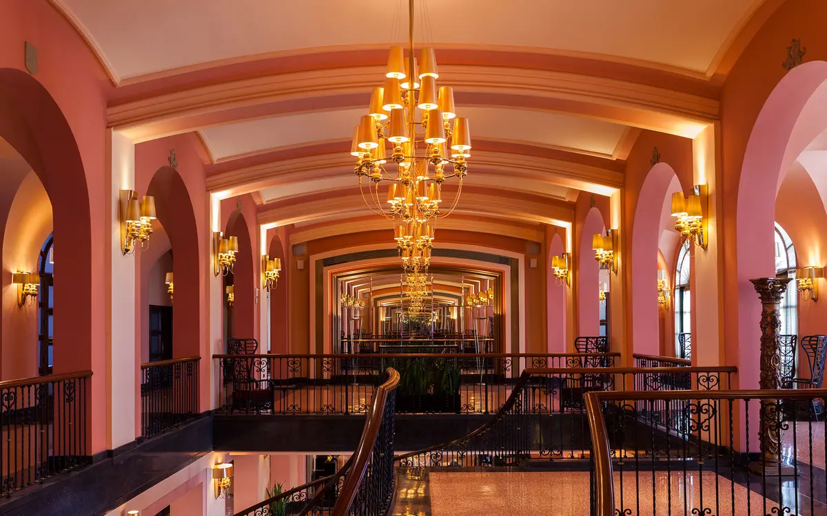 Arched double height lobby with a chandelier and a balustraded gallery above