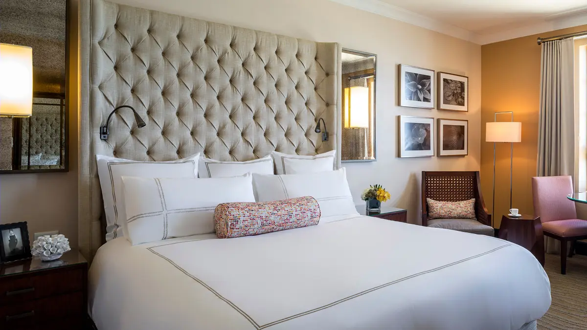 Guest room with a buttoned headboard, white bedding and framed prints on the wall