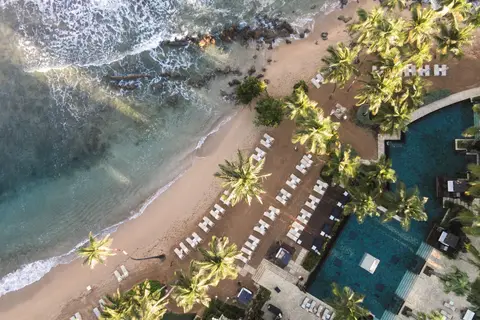 Aerial view of the Dorado Beach shoreline with the resort pool deck behind the sand