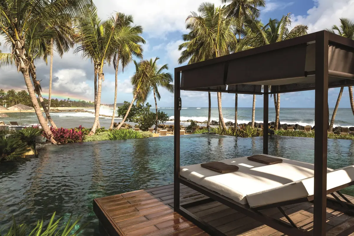 Infinity pool with a shaded daybed cabana looking out to the Atlantic