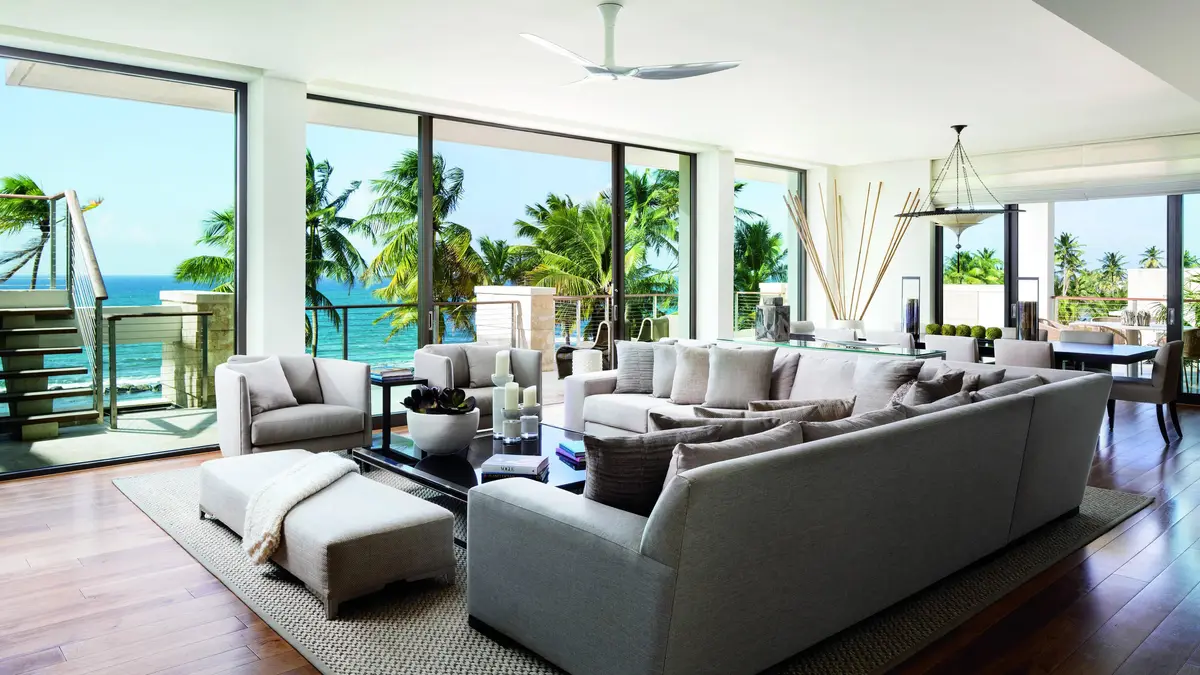 Penthouse living room with pale sofas and a wall of glass facing the palms and sea