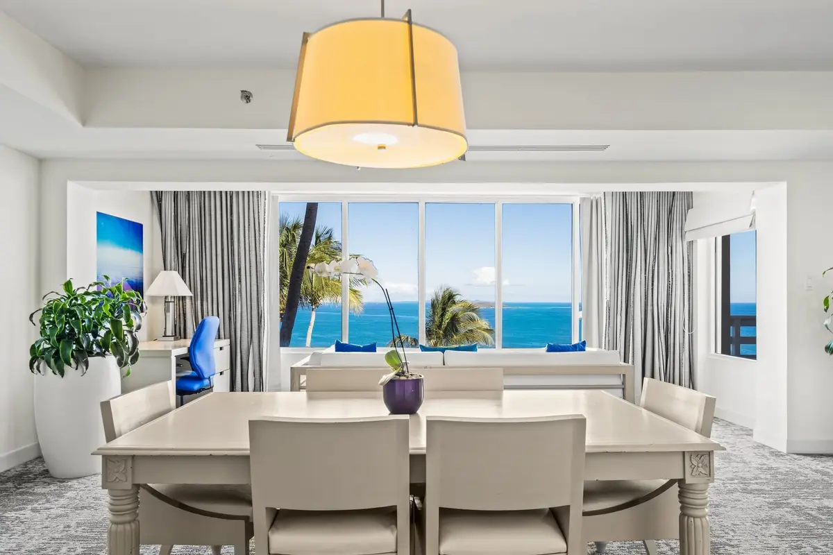 Dining table and seating area in a Las Brisas parlour suite with the sea through the windows