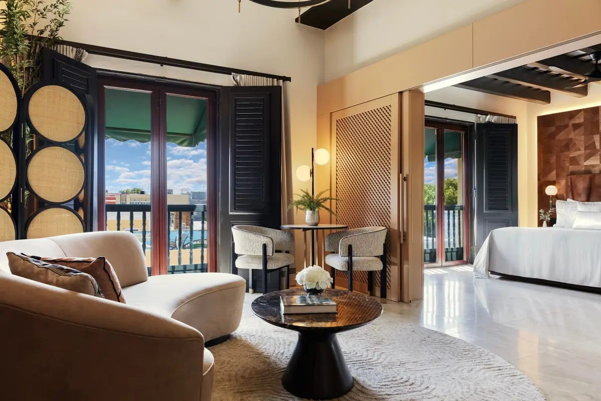Signature suite with a curved sofa, dark shutters and a bed visible through the arch beyond