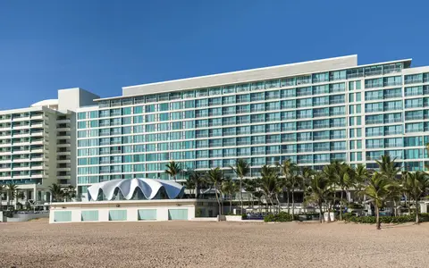 The glass fronted La Concha tower seen from the sand with the shell shaped restaurant below it