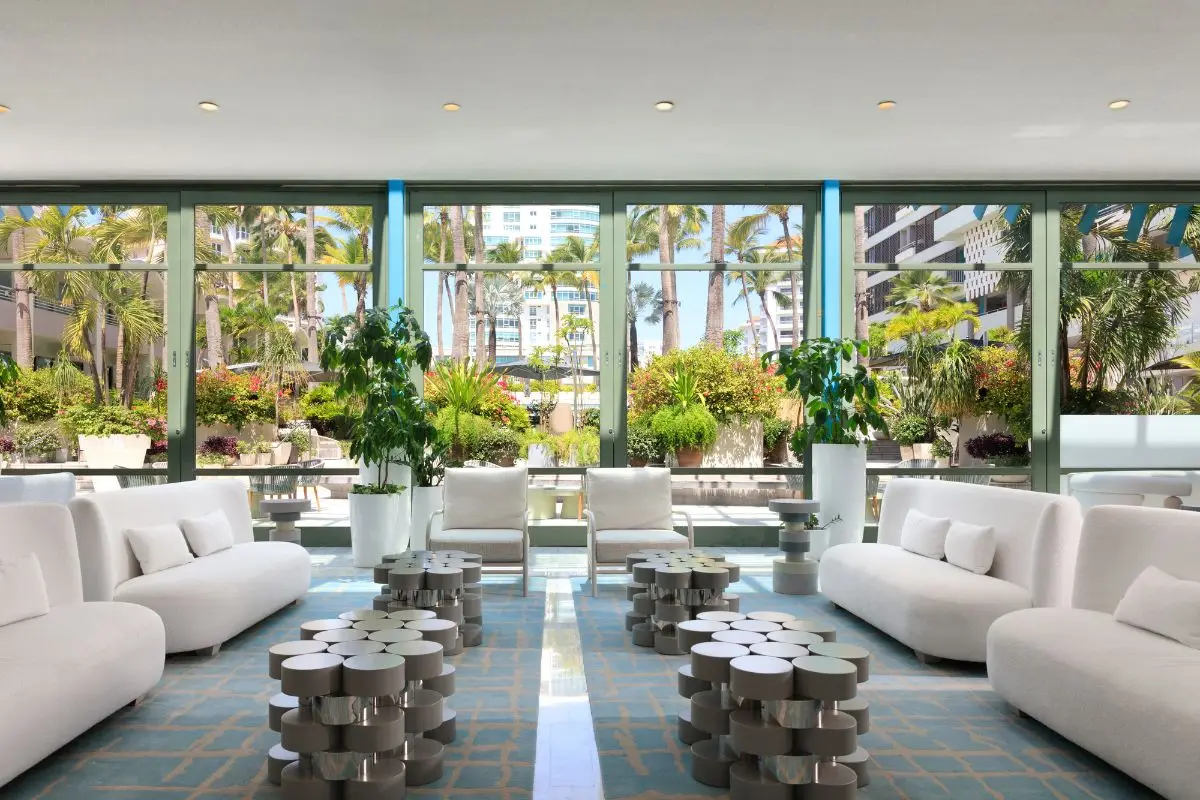 Open lobby lounge with white sofas and planters looking through to the beach