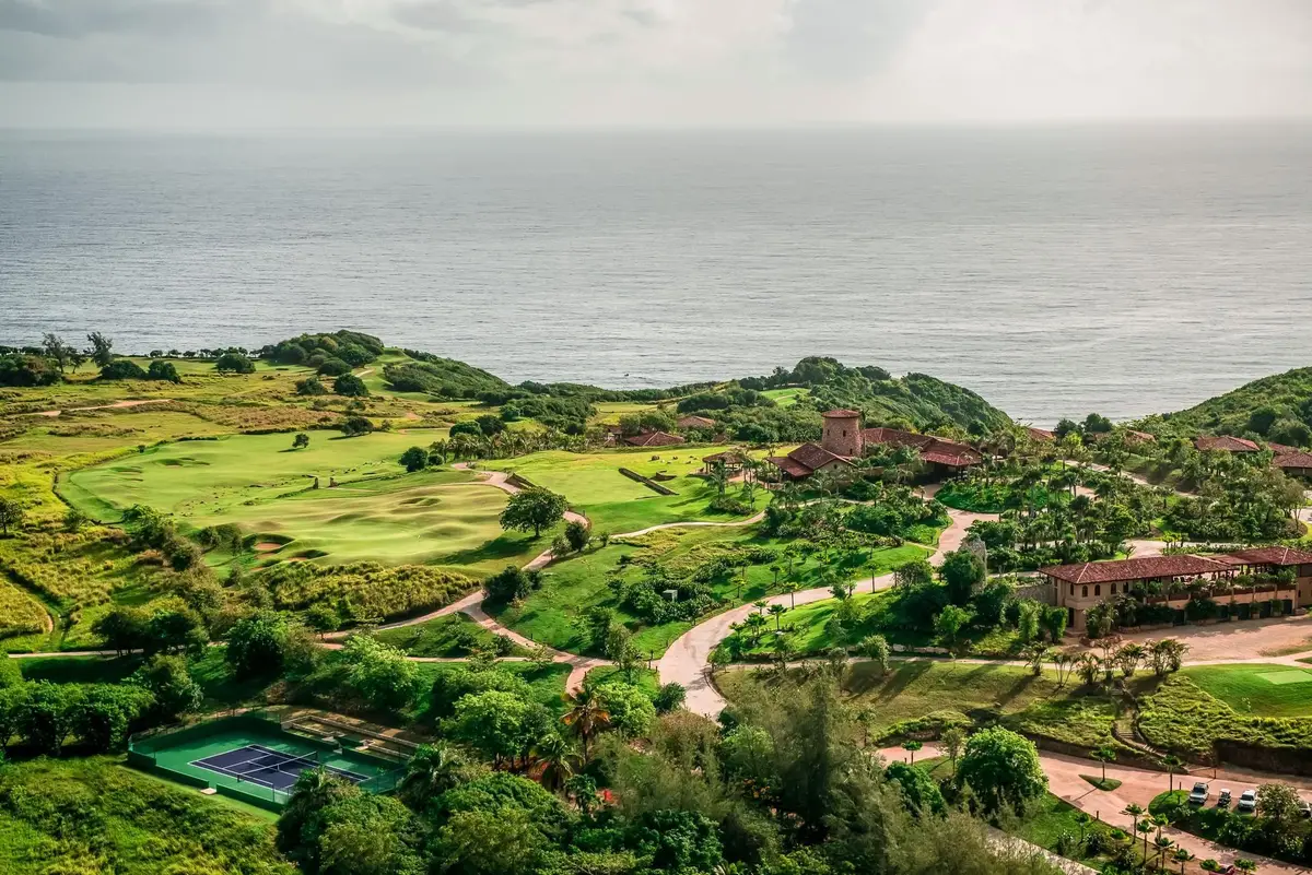 Golf fairways and scrub running along the clifftop above a grey Atlantic