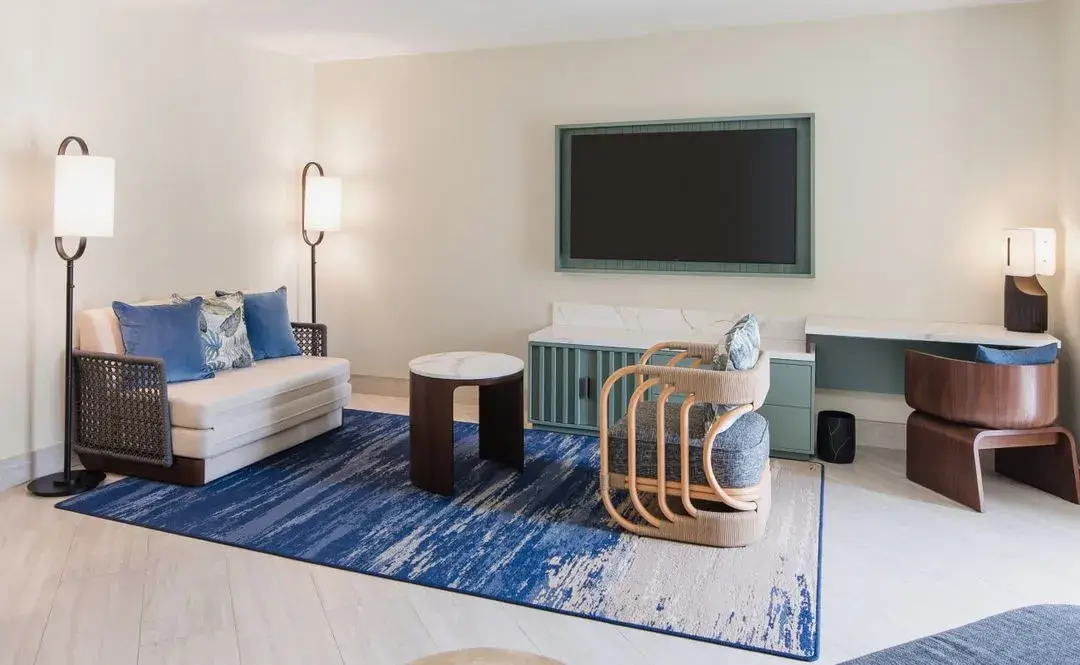 Junior suite sitting area with a sofa, a rattan chair and a blue patterned rug