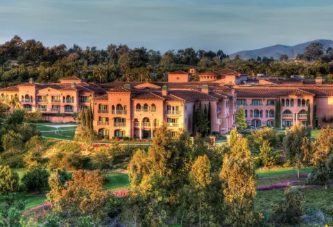 The pink Mediterranean buildings of Fairmont Grand Del Mar seen across the canyon