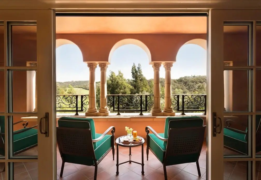A suite terrace framed by stone columns and arches looking out over green hills