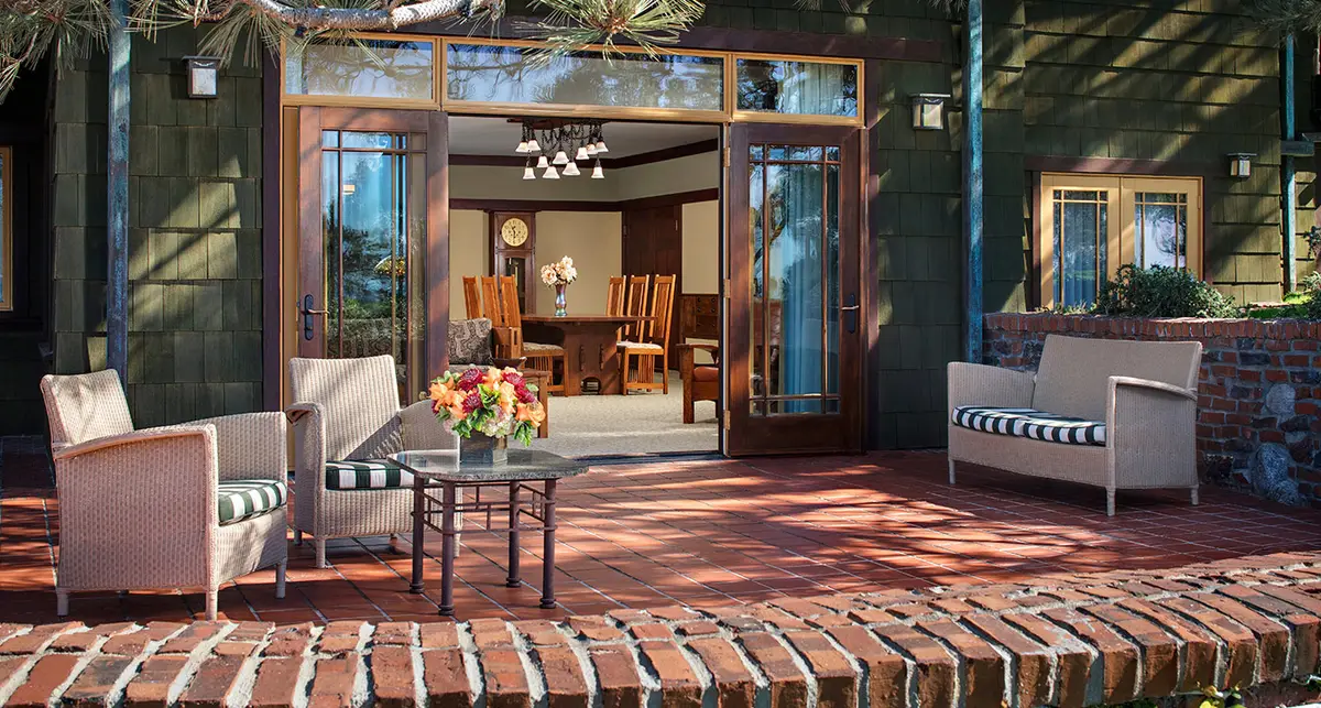 A brick terrace with cushioned seating outside open timber doors into a lounge