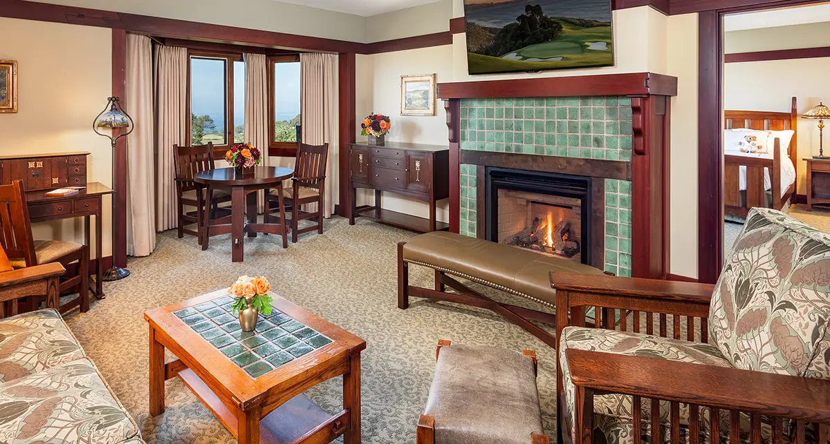 A suite sitting room with a green tiled fireplace, a Stickley armchair and art glass lamps