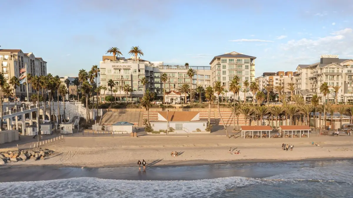 The resort seen from the wet sand at low tide with palms along the front