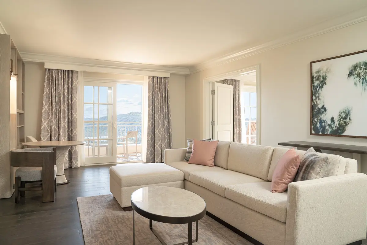A suite living room with a cream sofa, pale rug and glass doors onto a terrace