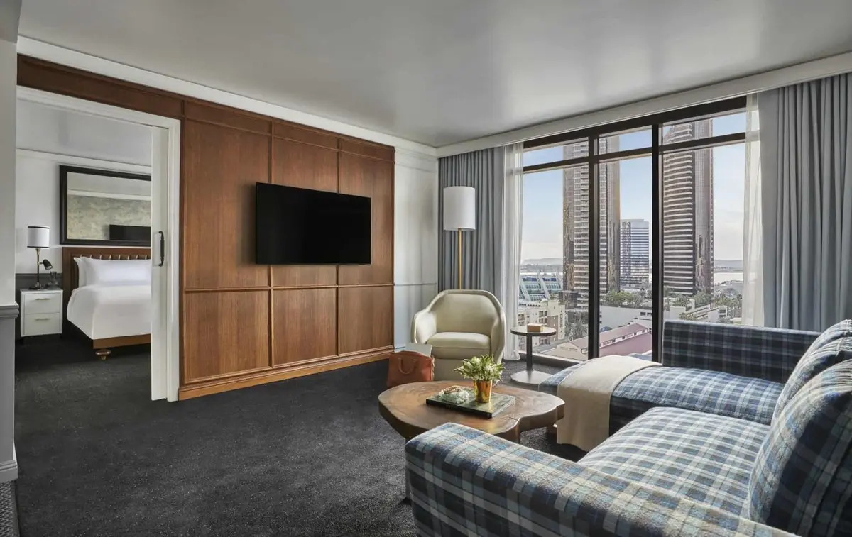 A suite sitting room with a plaid sofa, timber panelling and windows onto the skyline