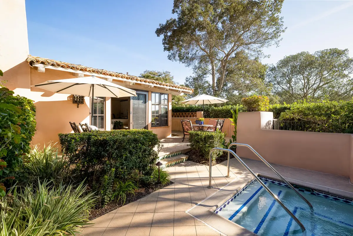 A private walled patio with a sunken whirlpool, loungers and hedging