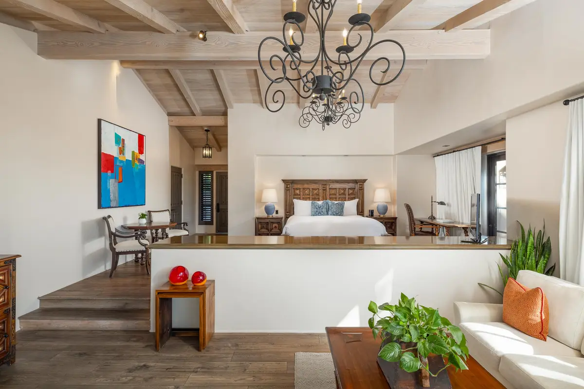 A casita bedroom with a carved wooden headboard, beamed ceiling and a sunken sitting area