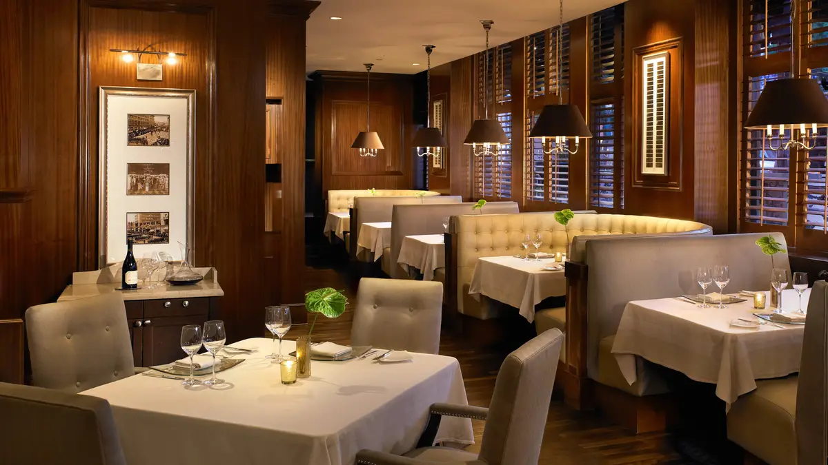 A panelled dining room with cream banquettes, white tablecloths and low lamps
