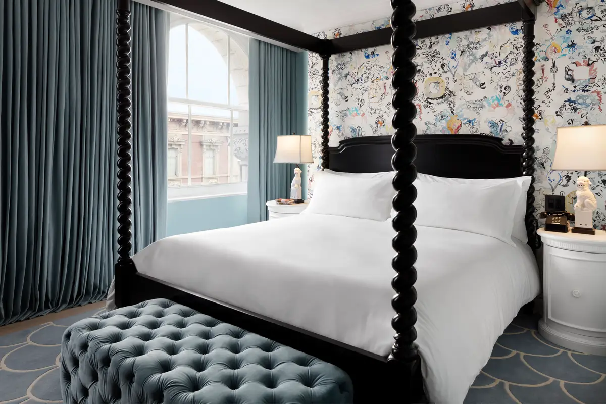 The bedroom of a First Lady suite at Riggs with a painted headboard and tall windows