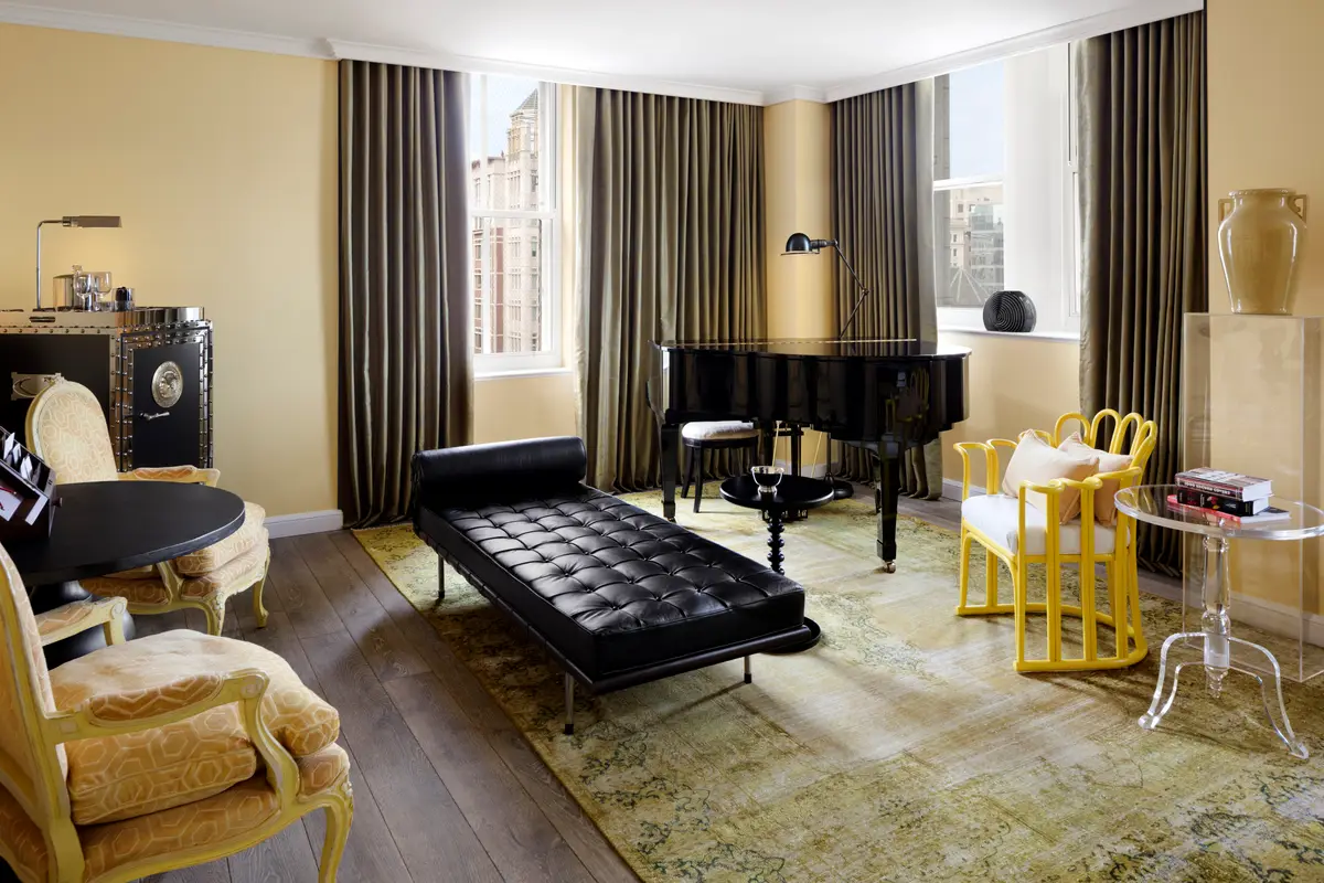 A yellow sitting room in a First Lady suite at Riggs with a grand piano and a leather bench