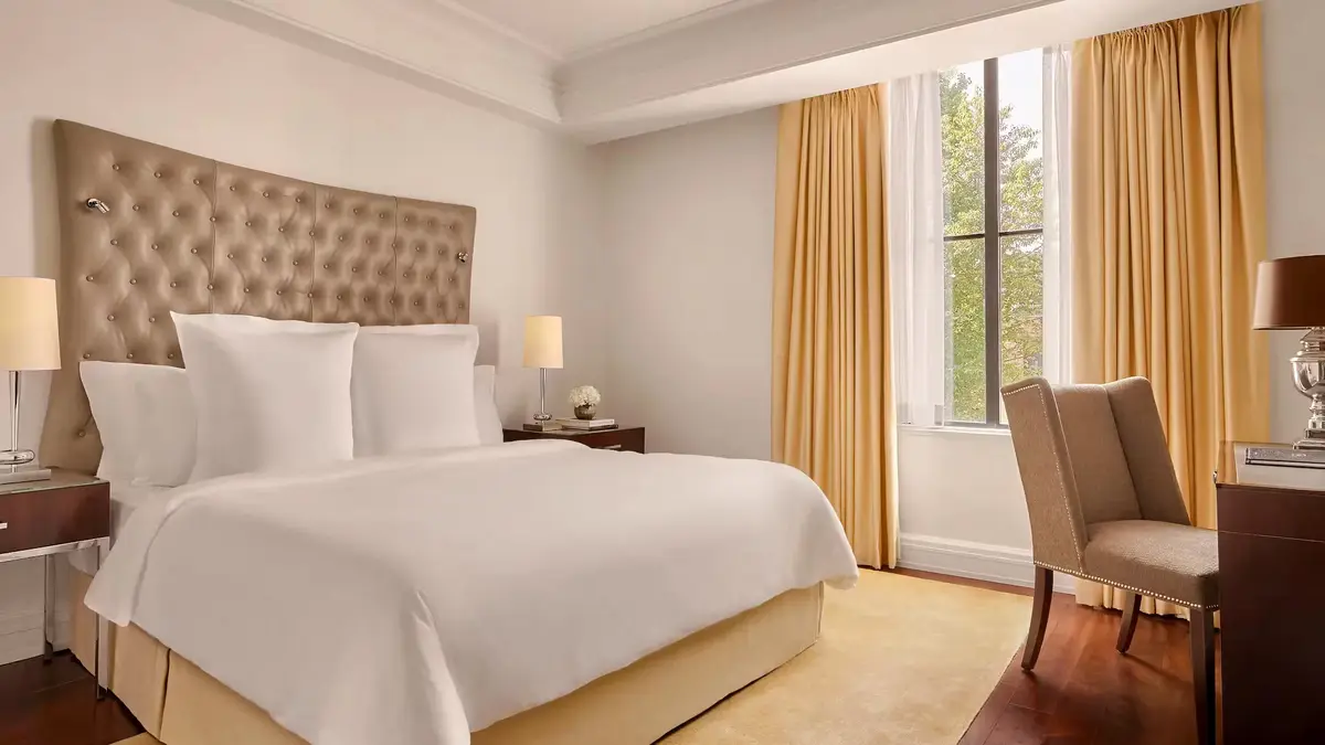 A superior king room at the Rosewood Washington DC with dark wood floors and a tufted headboard