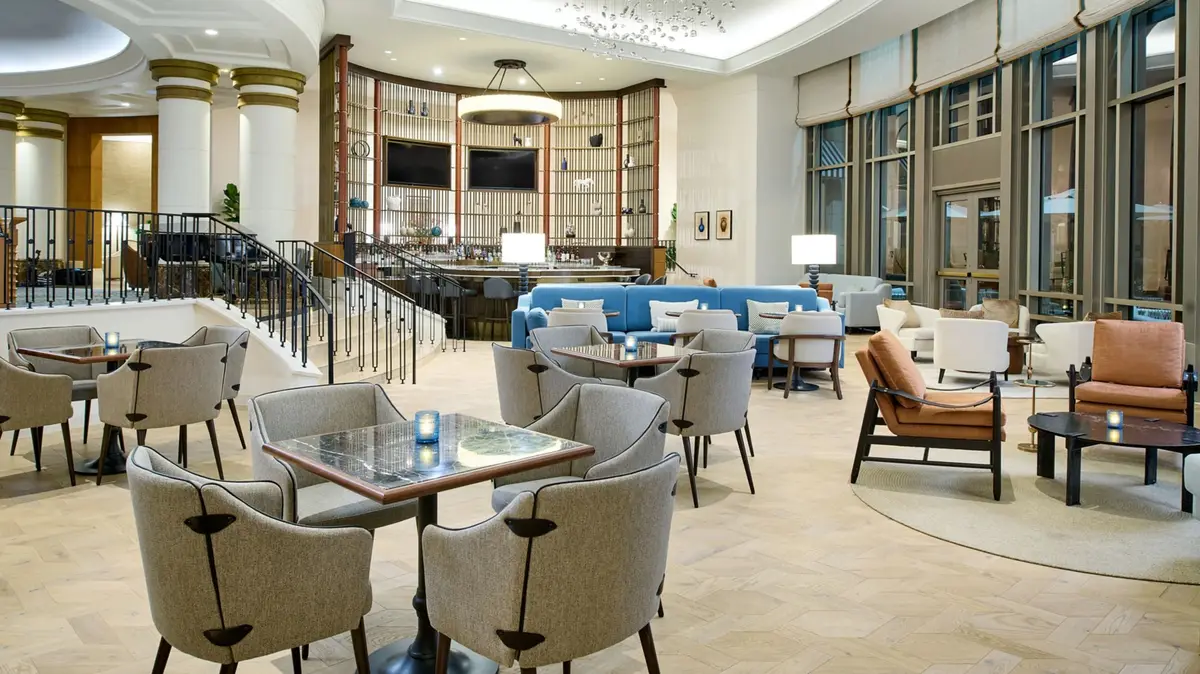 A double height lounge with floor to ceiling windows looking onto trees and water