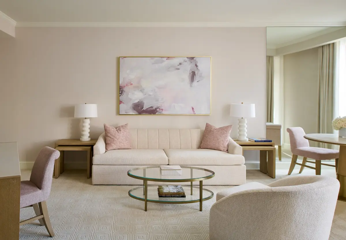 A suite living room with a long cream sofa and a round dining table by the window