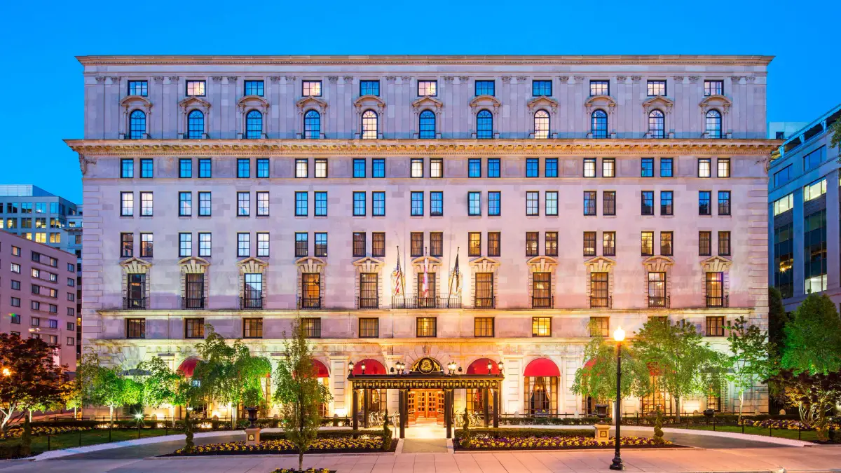 The limestone facade of the St Regis Washington DC lit at dusk with planted window boxes