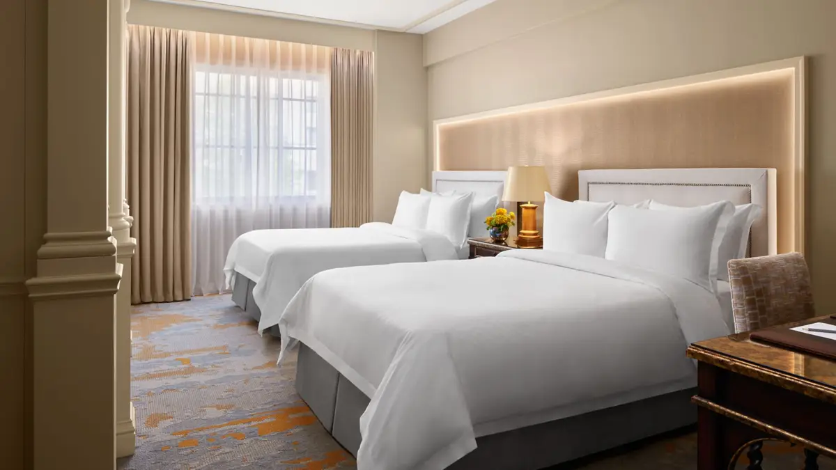 An Astor deluxe room at the St Regis Washington DC with twin beds and a gold patterned carpet