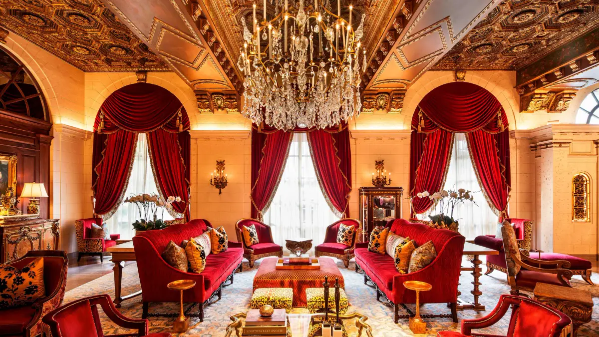 The grand lobby of the St Regis Washington DC with red sofas, gilt panelling and chandeliers
