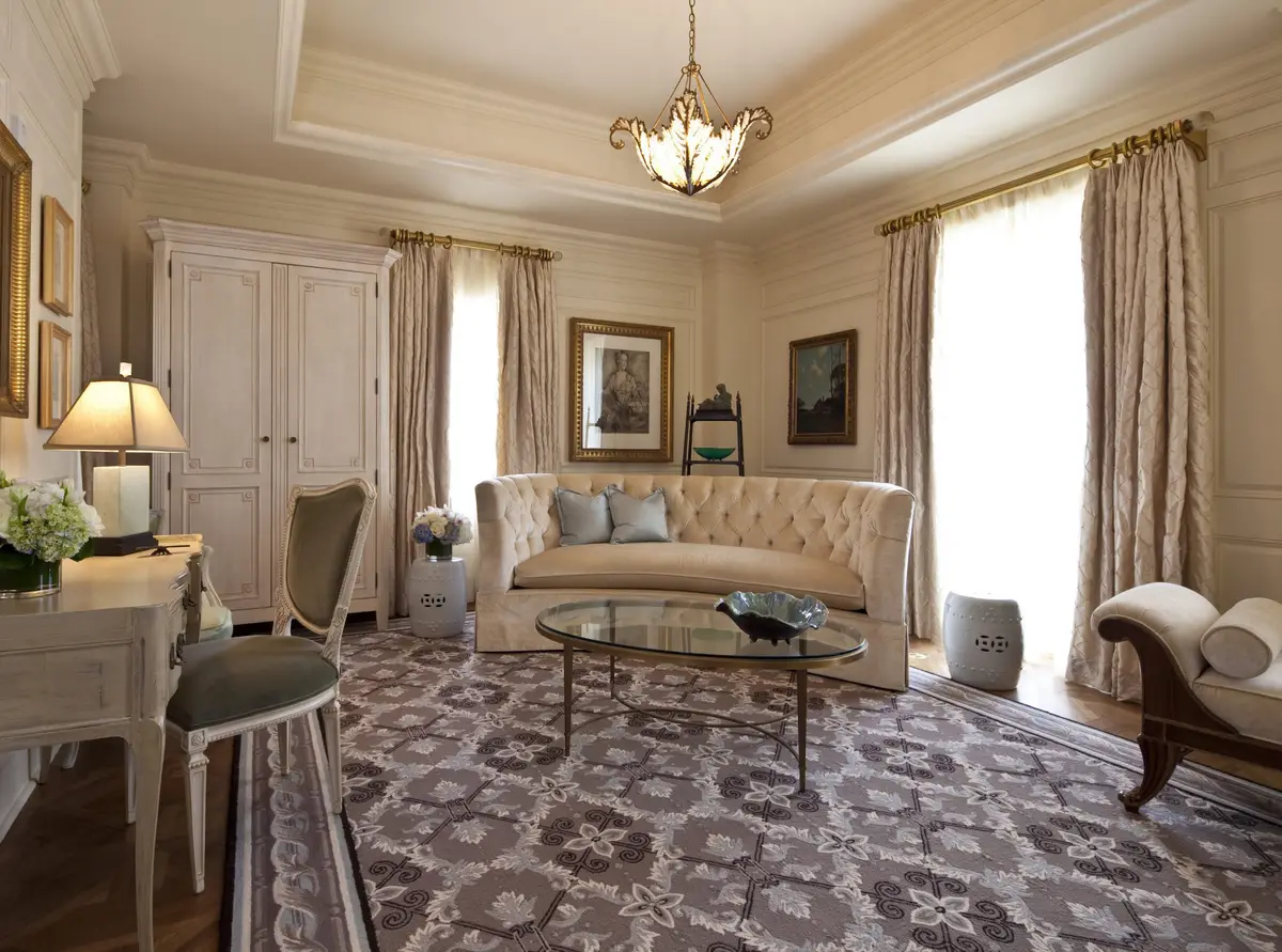 A pale sitting room in a suite at The Jefferson with a tufted sofa and long curtains