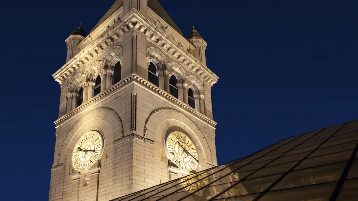 The lit clock faces of the Old Post Office tower against a dark blue sky