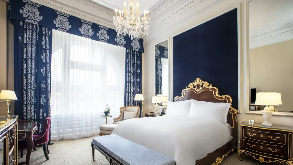 A deluxe king room at the Waldorf Astoria Washington DC with an arched window and a carved headboard