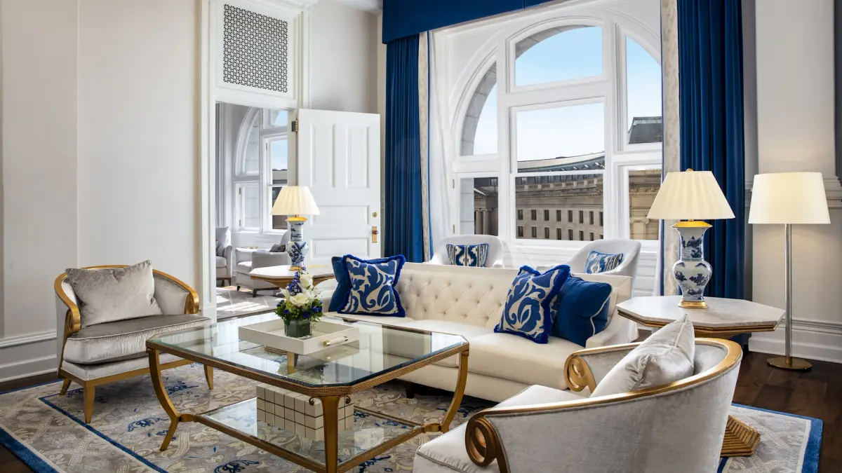 The sitting room of the Franklin Suite with blue drapes and a glass coffee table