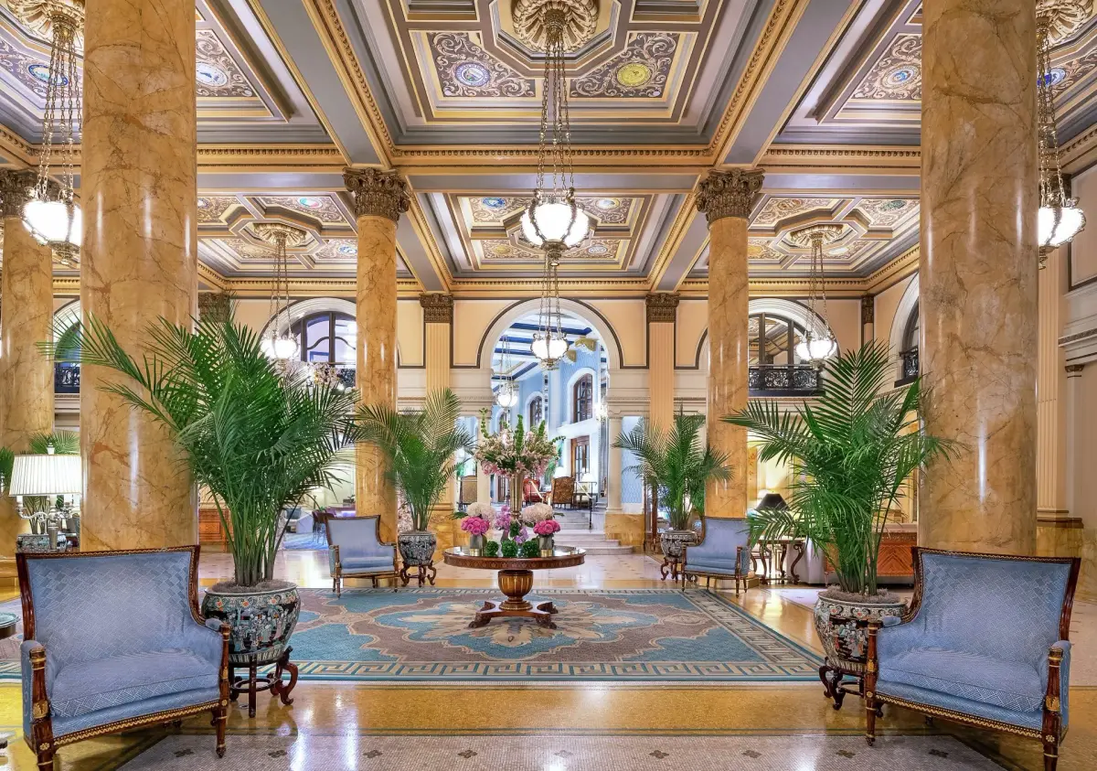 The Willard lobby with marble columns, a painted coffered ceiling and potted palms