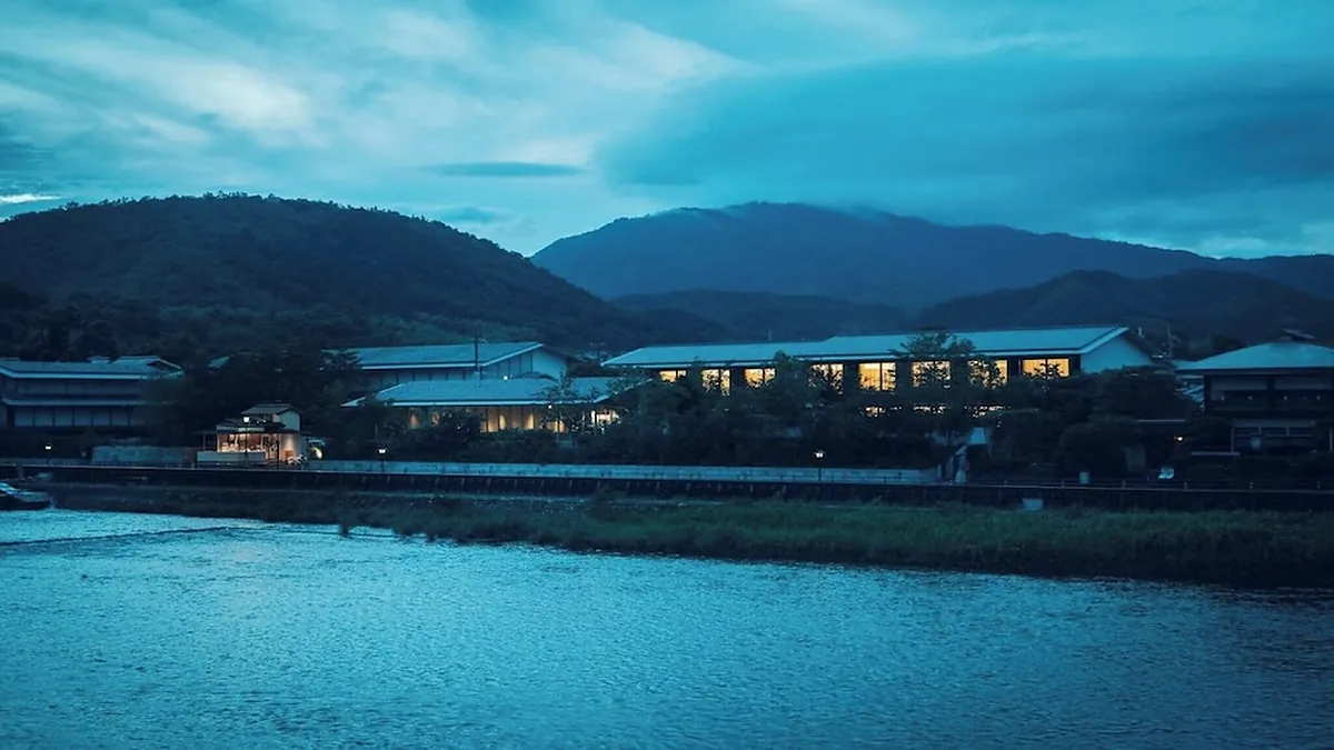 MUNI KYOTO, the hotel lit at dusk across the river below the hills, Kyoto