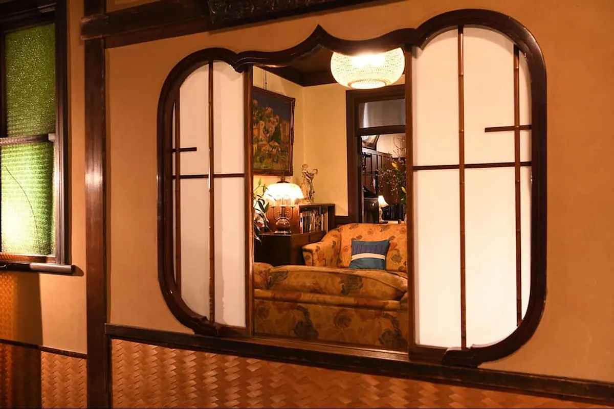 Seikoro Ryokan, the arched window seen from the garden with the room lit inside, Kyoto