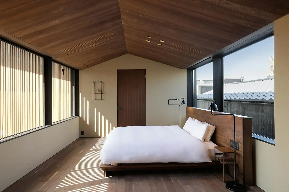 SOWAKA, a bed in a timber ceilinged room with shuttered window, Kyoto